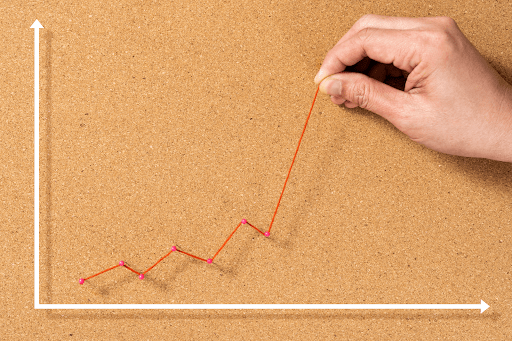 A person creating a graph with string on a cork board