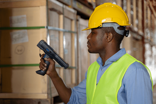 A man wearing a hardhat and using a scanner in his hand