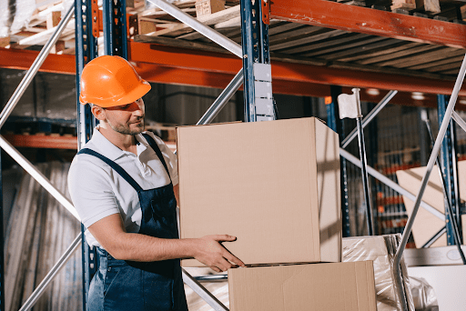 A man wearing a hard hat and stacking boxes in a warehouse