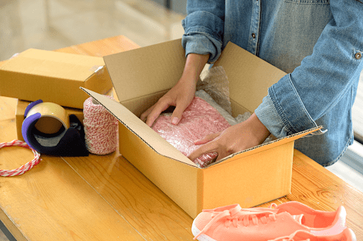 A man packing items into a box to be sealed for shipping